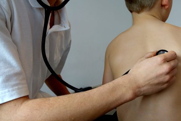Médico examinando os batimentos cardíacos de uma criança com suspeita de coqueluche
