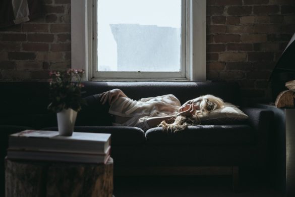 Absenteísmo: mulher deitada no sofá com rosto transparecendo tristeza