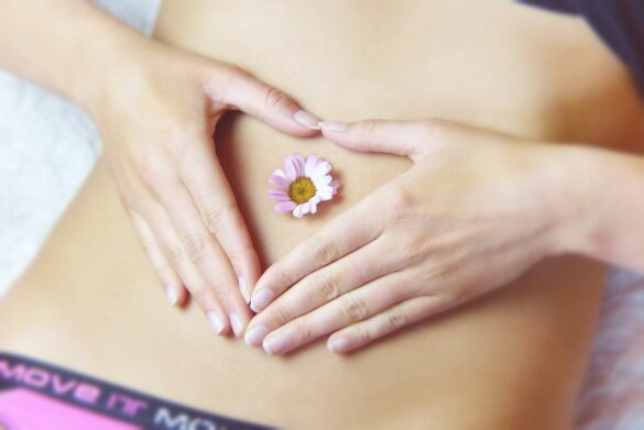 Endometriose: foto de uma mulher com as mãos sob o abdome com uma flor no centro da barriga